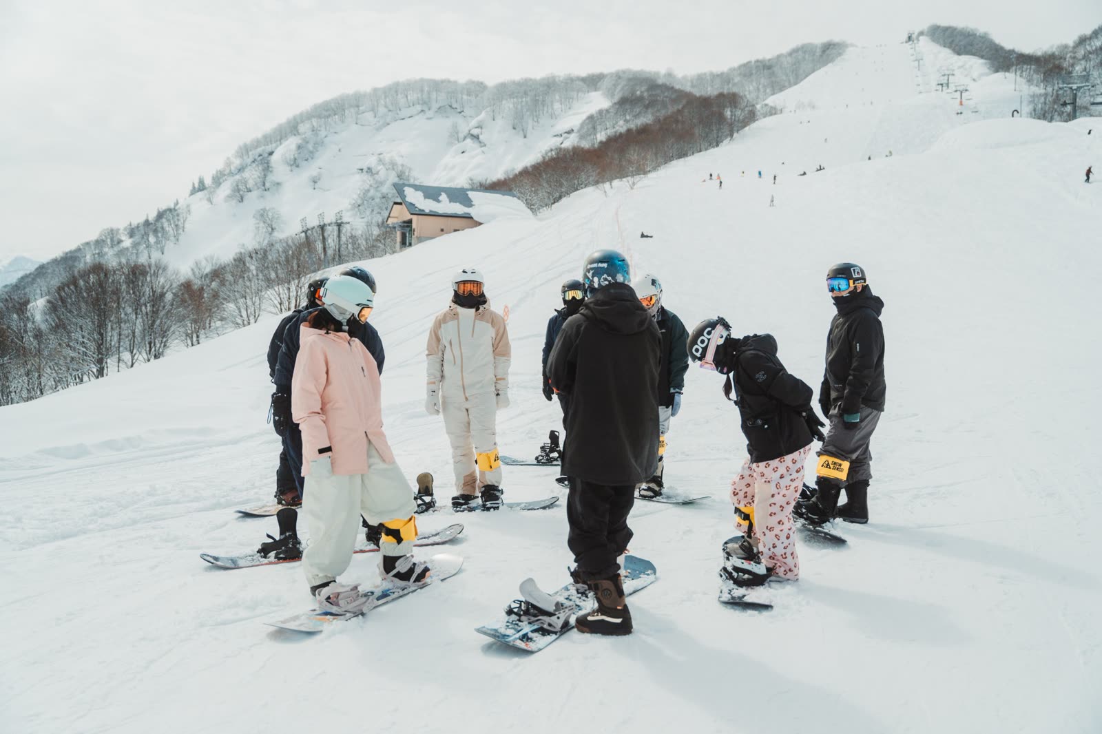 Coaches briefing a group of beginner snowboarders on the slope